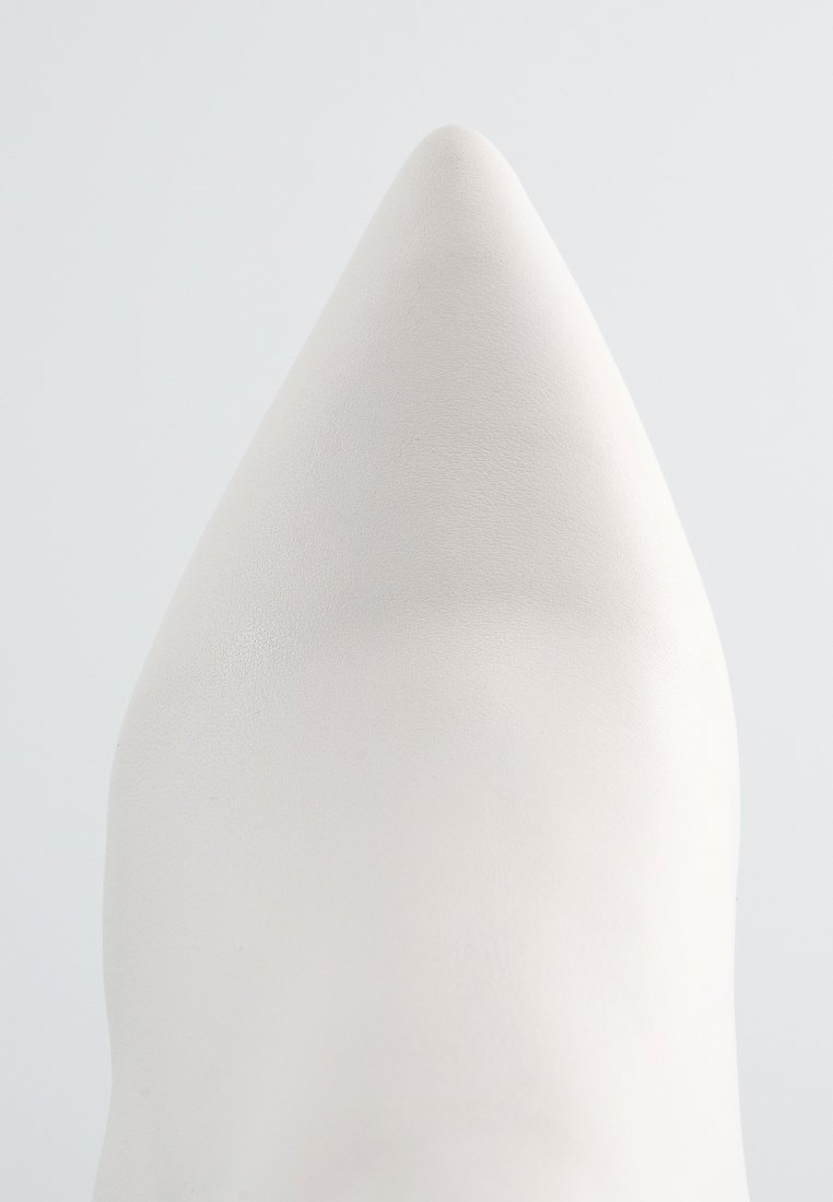 Weiße, spitze Schuhe aus einer glatten, matten Textur. Der Schuh weist ein schlankes Design auf, das eine minimalistische und elegante Silhouette betont.