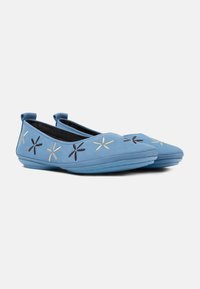 Helleblaue Ballettschuhe aus weichem Material, mit schwarzer und goldener floralem Stickerei im Zehenbereich und einer flexiblen Gummisohle.