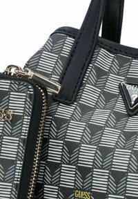 Sac à main noir et gris à motif avec une finition texturée, doté d'une fermeture éclair dorée et d'un accent en forme de logo triangulaire.