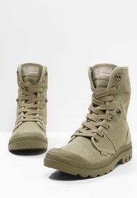 Khaki płócienne botki za kostkę z wzmocnionym czubkiem, płaskimi sznurowadłami, metalowymi oczkami i teksturowaną gumową podeszwą; posiadają logo Palladium na języku.