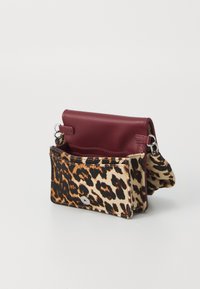 Sac bandoulière en imprimé léopard avec un rabat supérieur en cuir bordeaux, fermeture à bouton argenté et une sangle robuste pour le transport. Tissu texturé.