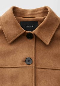 Brown suede coat with wide collar and two large black buttons, showing brand label "OPUS" inside the collar.
