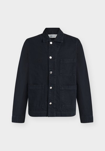 Veste noire avec col, fermeture à boutons devant et trois grandes poches, présentée à plat sur fond blanc.