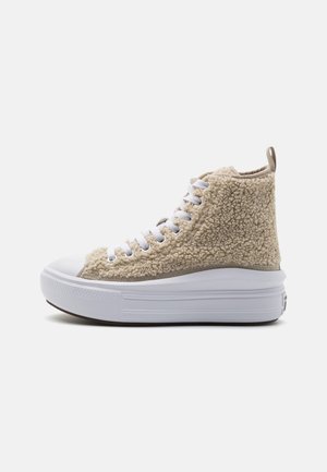 Baskets montantes avec texture en polaire beige, bout en caoutchouc blanc, semelle plateforme épaisse blanche et lacets blancs.