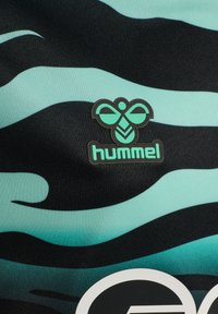 Svart och teal kamouflage-tröja med texturerat tyg och en framträdande grön logo av en bi samt texten "hummel" på den nedre delen.