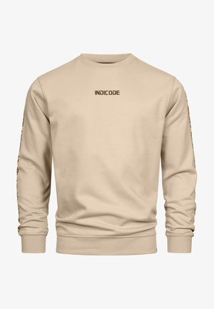 Beige pulóver, puha anyagból, hosszú ujjakkal. Az elején "INDICODE" logóval és szöveggel a ujjakon. Klasszikus szabás.