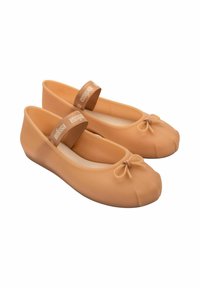 Bailarinas de goma marrón claro con punta redonda, que presentan un pequeño lazo en la parte delantera y una tira elástica marrón etiquetada "Melissa". Textura suave.