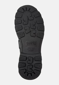 Black rubber shoe sole with textured grip pattern and prominent logo reading "Camper Bridge XTRAGRIP." Features deep grooves for traction.