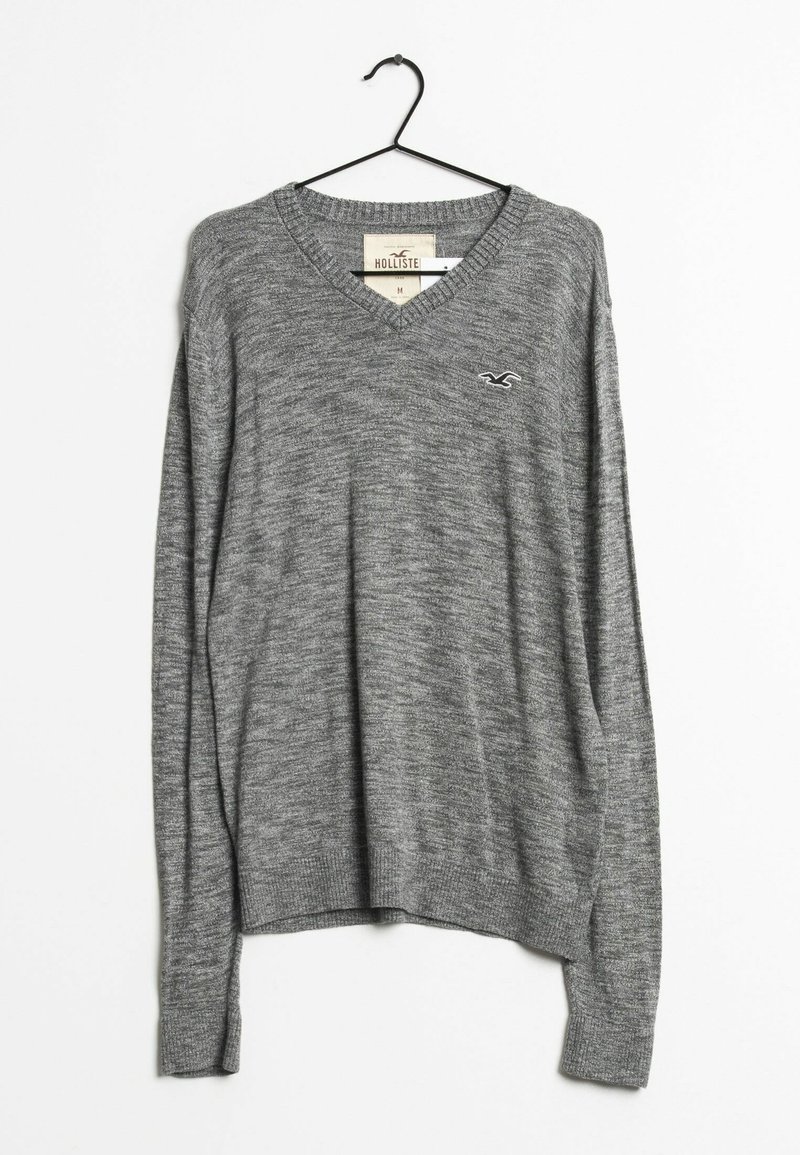 Grå v-ringad tröja gjord av mjukt stickat material. Har långa ärmar och ribbad nederkant. Liten logotypdetalj på vänster bröst.