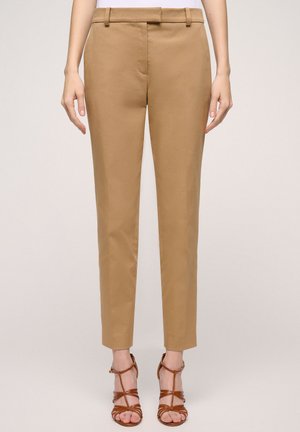 Khaki skinny broeken met een gladde textuur, riemlussen en een getailleerde pasvorm, gecombineerd met bruin gespsandalen.