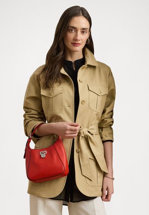 Casaco de algodão bege com dois bolsos no peito e um laço na cintura. Acompanhado por uma bolsa de couro vermelha com uma pega no topo e ferragens prateadas.