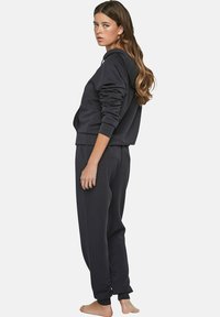 Donkergrijze hoodie en bijpassende joggers, gemaakt van zachte stof met een relaxte pasvorm en geribbelde manchetten, voorzien van een capuchon en zijzakken.