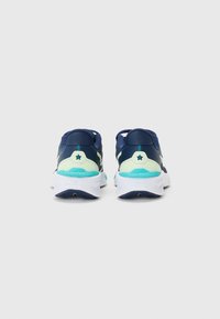 Baskets de course navy avec des accents bleu canard, tige texturée et semelle blanche. Présente un emblème en étoile sur le talon et un design rembourré.