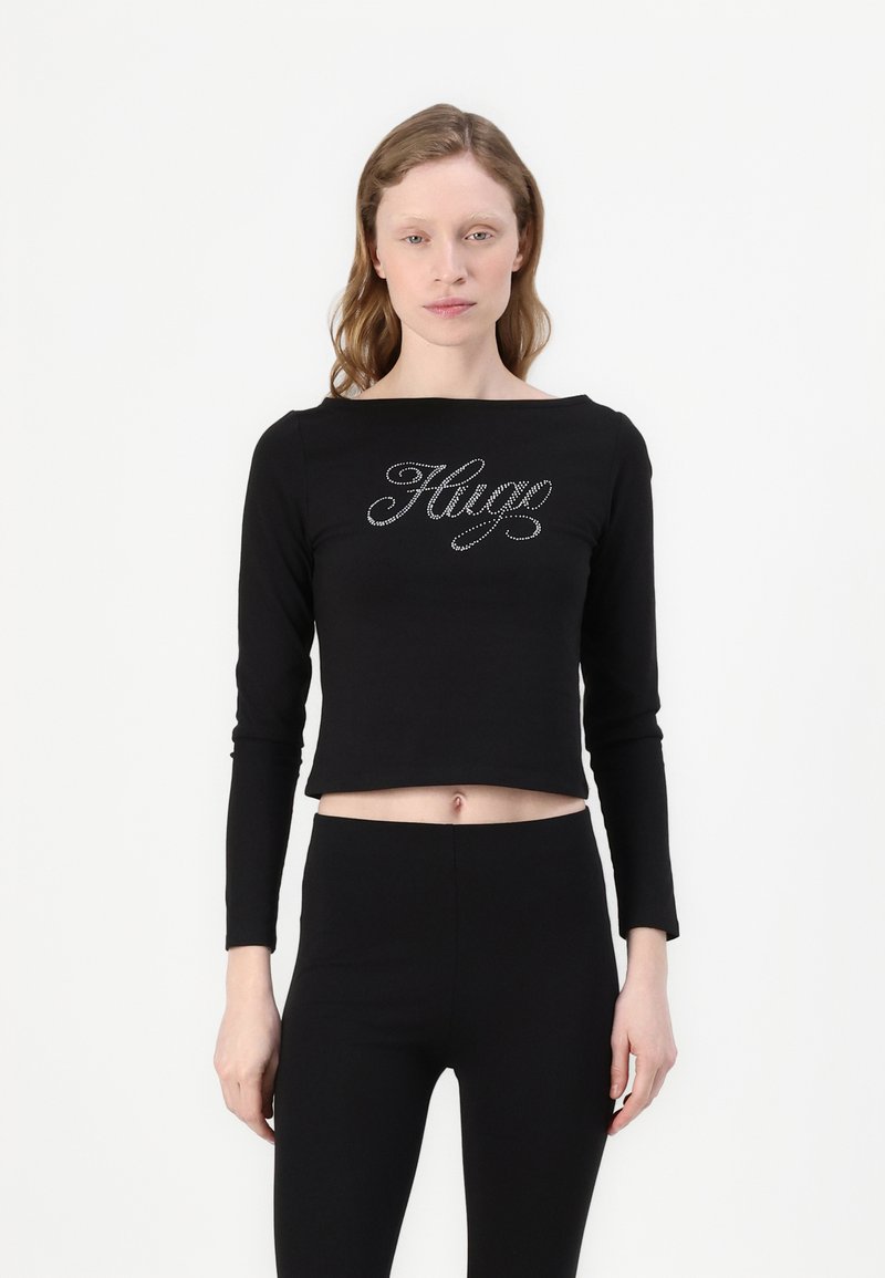 Svart langermet cropped topp med et krystalldekorert "Hug"-logo over brystet, laget av et mykt og stretchy stoff.