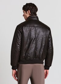 Braune Lederjacke mit strukturierter Oberfläche, hohem Kragen und gerippten Bündchen. Verfügt über eine klassische Bomberjacken-Silhouette.