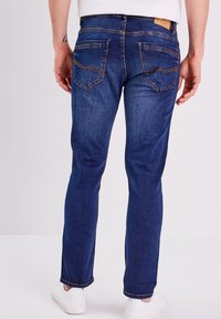 Miestne tmavomodré džínsy vyrobené z denimu, s bočnými vreckami a vyšitémi detailami, strih so štrkovými nohavicami a stredne vysoký pás.