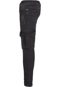 Mustad denim kitsas teksad, millel on kulumisjälgedega detailid ja cargo-stiilis kangatooted reie piirkonnas, omavad klassikalist viit taskut.