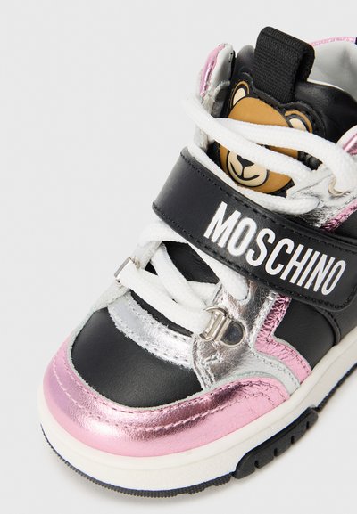 Black and silver high-top sneaker with a pink metallic accent, white laces, and a bear logo on the tongue; branding on the strap.