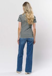 Mustavalkoinen raidallinen lyhythihainen paita, yhdistetty sinisiin leveälahkeisiin farkkuihin. Malli on vartalonmyötäinen ja kangas teksturoitua.