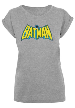 Harmaa t-paita, jossa on suuri sininen ja keltainen "BATMAN" -logo, jossa on lepakkosiluetti ja pyöreä pääntie. Pehmeä, rento materiaali.