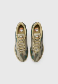 Green and beige sports shoes with mesh upper, round laces, patterned design, and visible Air Max branding on the tongue.