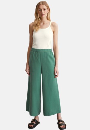 Groene wijde broek van lichtgewicht stof, met een elastische tailleband en zijzakken, gecombineerd met een wit tanktop en zwarte sandalen.