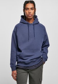 Sudadera azul marino hecha de material suave, con un bolsillo tipo canguro en la parte delantera, cordones ajustables y puños acanalados. Diseño de ajuste casual.