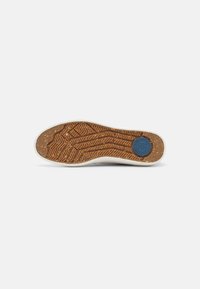 Rubberen buitenzool met een gestructureerd visgraatpatroon in lichtbruin met donkerbruine accenten en een blauw cirkellogo in het hielgebied.