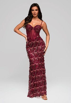 Robe de soirée bourgogne avec un corsage ajusté, des accents transparents et des franges superposées en perles et sequins. Bretelles spaghetti réglables.
