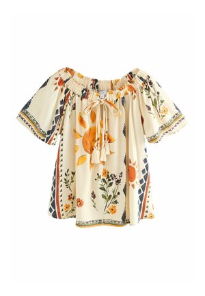 Blouse crème à épaules dénudées avec soleil orange, motifs floraux, liens à pompons et motifs géométriques en bordure sur les manches et l’ourlet.