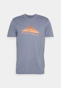 Camiseta de manga corta azul clara con logo triangular naranja y texto "Nike Trail" en el frente.