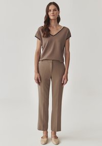 Haut brun à col en V avec des manches courtes, associé à un pantalon brun tailleur. Tissu doux avec un léger éclat, texture lisse et design minimal.