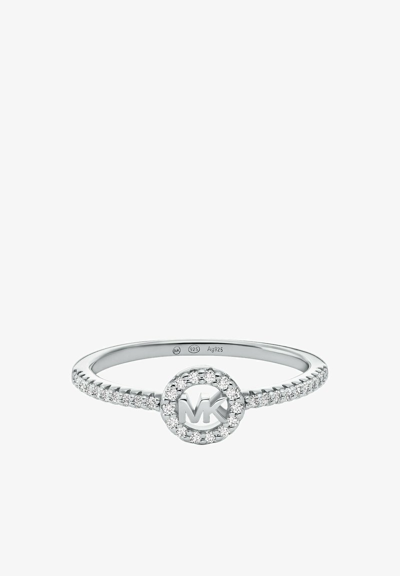 Bague en argent présentant un oval central avec le logo "MK" entouré de petites pierres claires. La bande a une texture perlée et une finition polie.