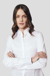 Biała koszula zapinana na guziki z klasycznym kołnierzykiem, długimi rękawami i gładką fakturą materiału, noszona przez osobę z założonymi rękami.