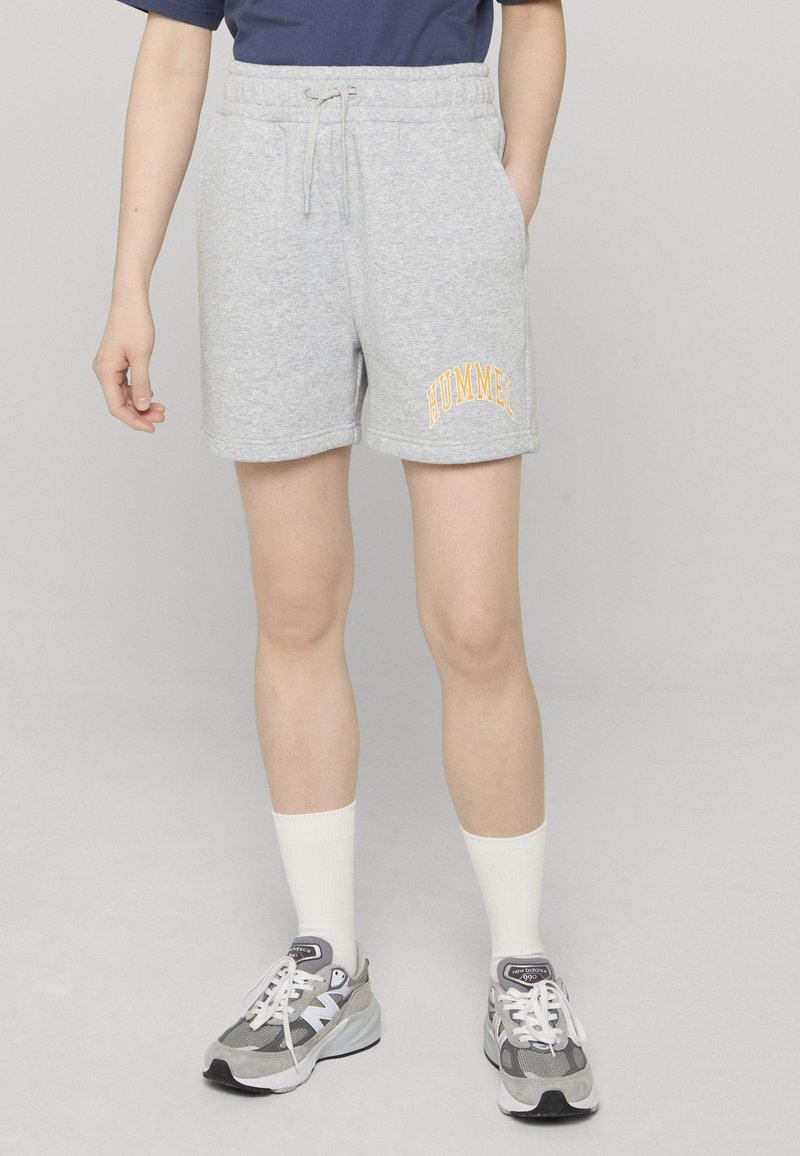 Shorts en coton gris avec une ceinture élastique et un cordon de serrage, arborant un logo "HUMMEL" jaune brodé sur le côté.