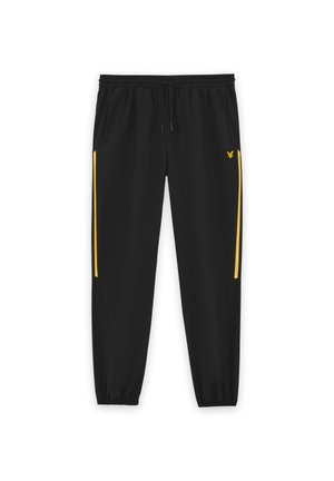 Pantalon de jogging noir avec taille et poignets élastiques, présentant des bandes latérales jaunes et un petit logo d'aigle jaune sur la cuisse droite.