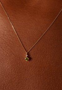 Gouden ketting met een fijne ketting en een hanger met een groene edelsteen en een kleine diamantaccent boven de zetting.