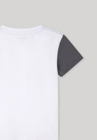 Camiseta de manga corta con un cuerpo blanco y mangas gris oscuro, fabricada en un tejido suave, que presenta un diseño simple y limpio.