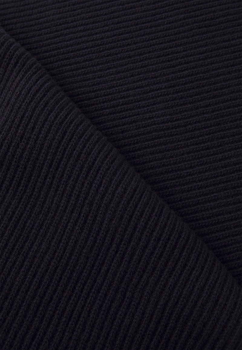 Czarna, żebrowana tkanina o teksturowanej powierzchni, z pionowymi liniami i miękkim, tkanym wyglądem. Prezentuje ciemny, jednolity kolor.