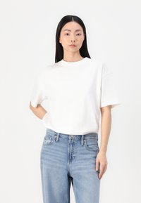 T-shirt bianca in cotone a maniche corte, con scollatura rotonda ribattuta e fit morbido, abbinata a jeans azzurri chiari con un classico design a cinque tasche.