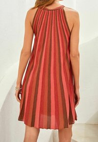 Robe sans manches avec des rayures verticales dans des tons de rose et de marron, coupe ample, dos plissé, et tissu doux et texturé.