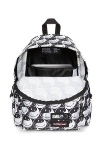 Mochila en blanco y negro con un patrón de caras sonrientes, material de tela, compartimento principal con una funda para computadora portátil, correas ajustables y asa superior.