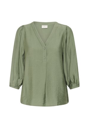 Blouse verte légère avec un décolleté en V, trois boutons et des manches bouffantes trois-quarts. Texture lisse avec un éclat subtil et des poignets froncés.