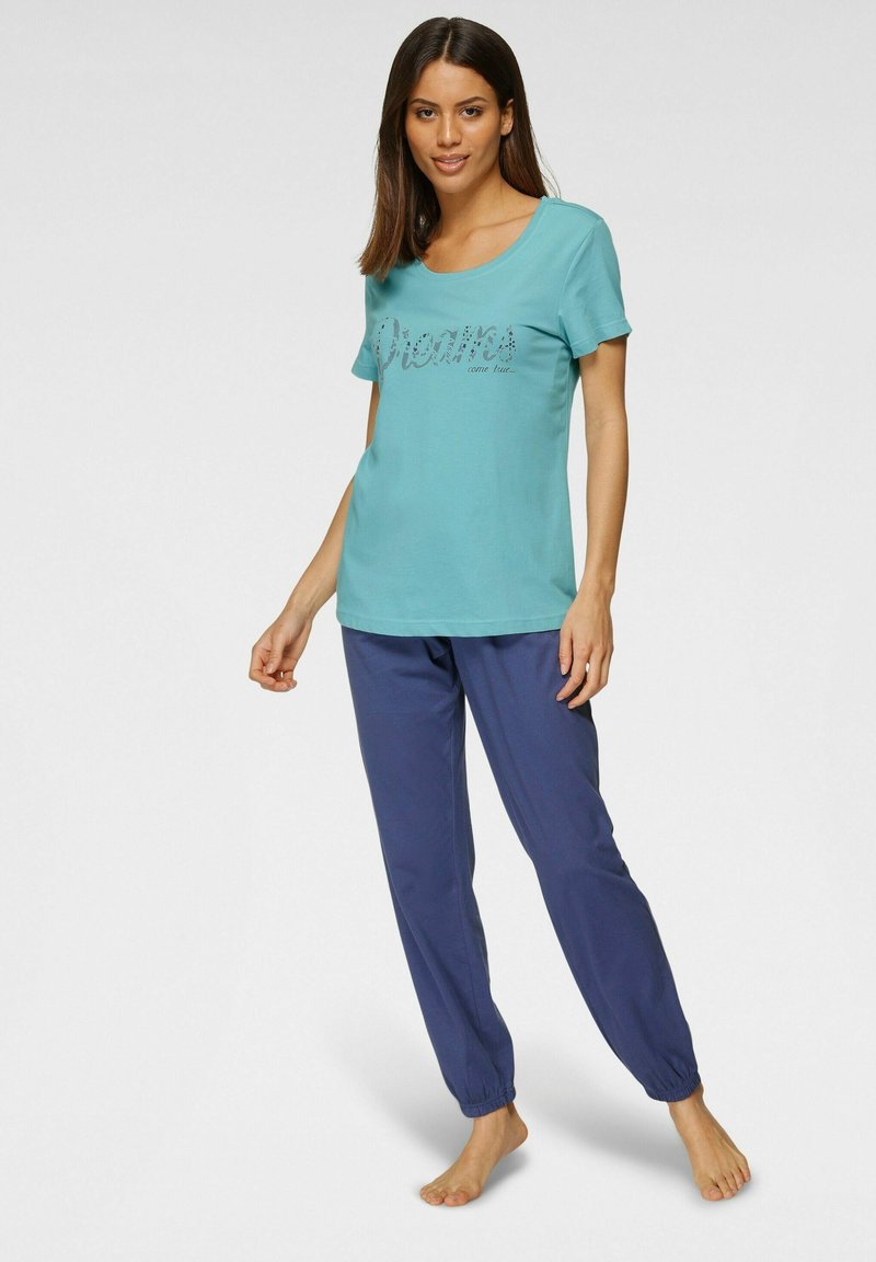 Light blue T-shirt with "Dreams come true" text in silver, paired with navy blue tapered pants with elastic cuffs.