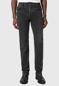 Mustat farkut, joissa on kapea malli, viiden taskun muotoilu, vyölenkit ja hienovarainen haalistunut pinta. Yhdistetty mustiin kenkiin.