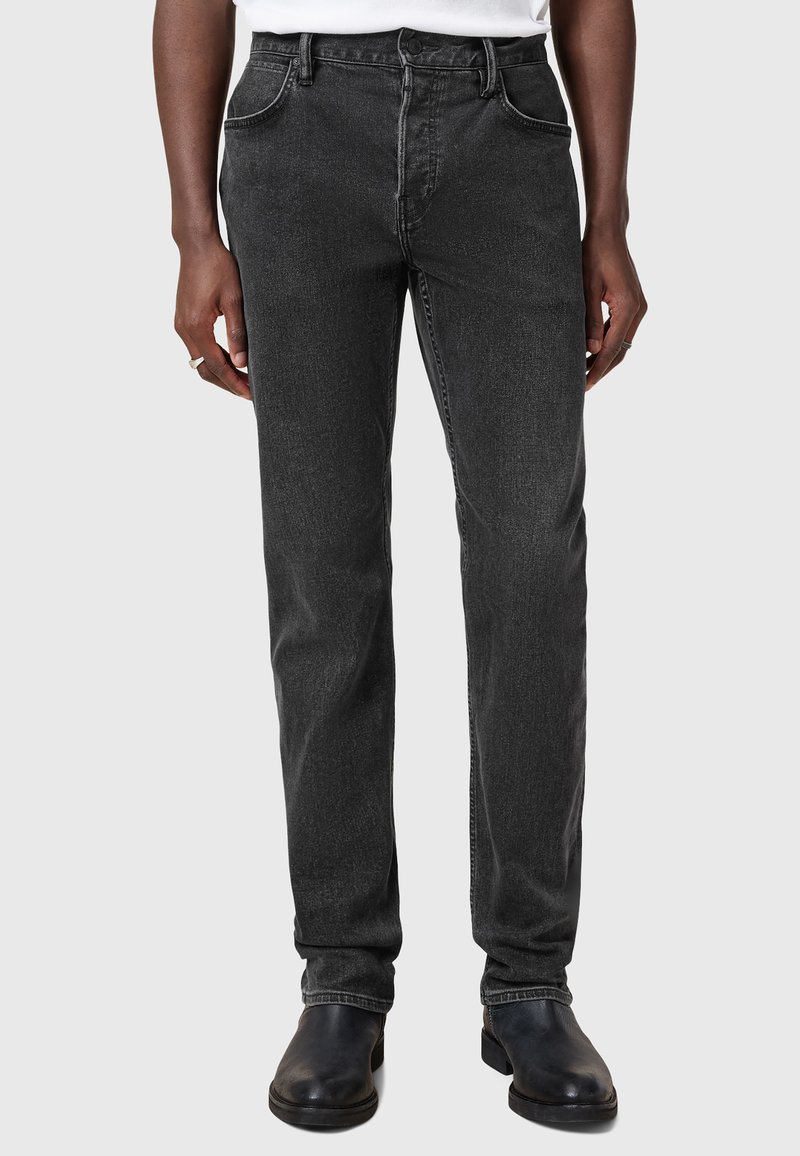 Mustat farkut, joissa on kapea malli, viiden taskun muotoilu, vyölenkit ja hienovarainen haalistunut pinta. Yhdistetty mustiin kenkiin.