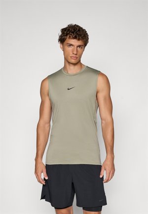 Top de sport sans manches en vert olive, fabriqué en tissu lisse avec un col rond et un logo Nike noir sur la poitrine. Associé à un short noir.