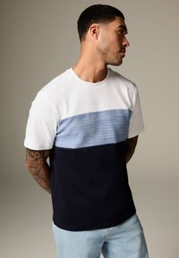 Kortärmad t-shirt med vit överdel, ljusblå horisontell rand och mörk marinblå nederdel. Mjukt tyg med en avslappnad passform.