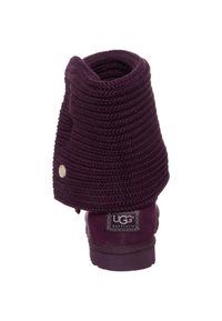 Botas UGG moradas con un puño de punto holgado, material de ante y punta redonda. Incluyen un botón decorativo y una etiqueta de marca en el talón.