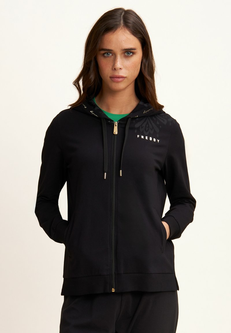 Sudadera con cremallera negra hecha de tejido suave, con un forro de capucha estampado, logo en el pecho y bolsillos seguros en los laterales.